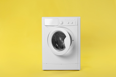 Modern washing machine on yellow background. Laundry day