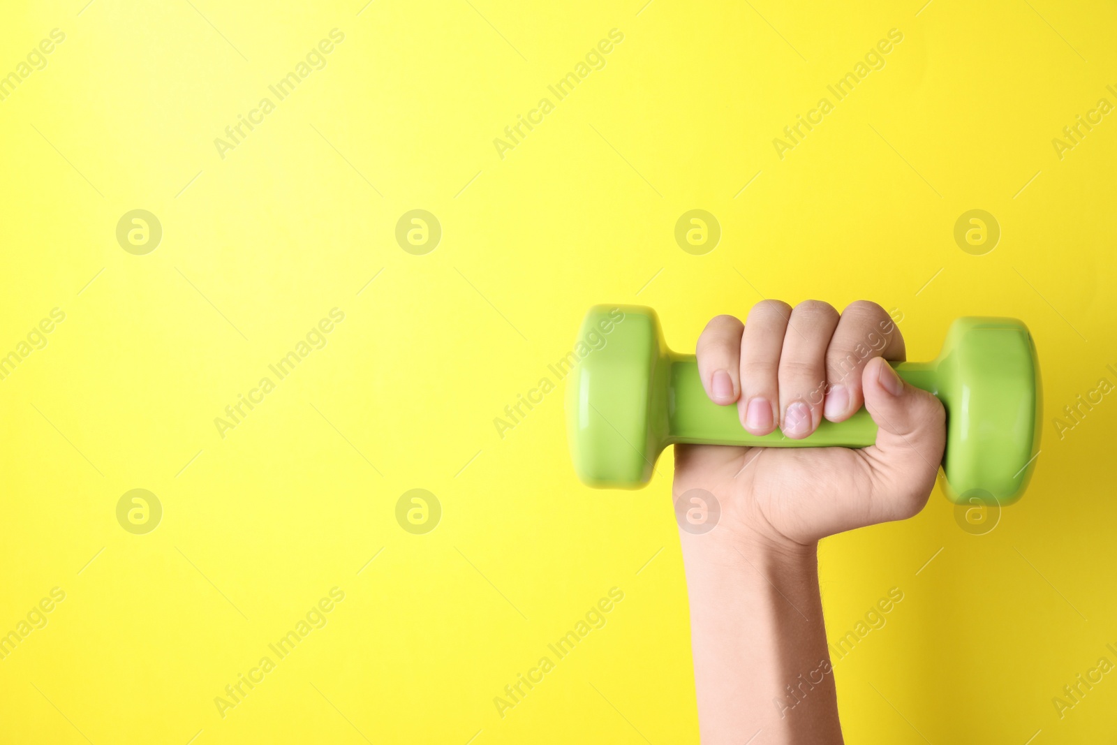 Photo of Woman holding vinyl dumbbell on color background, closeup with space for text