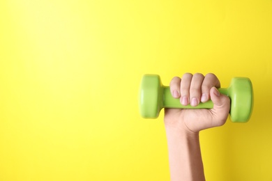 Woman holding vinyl dumbbell on color background, closeup with space for text