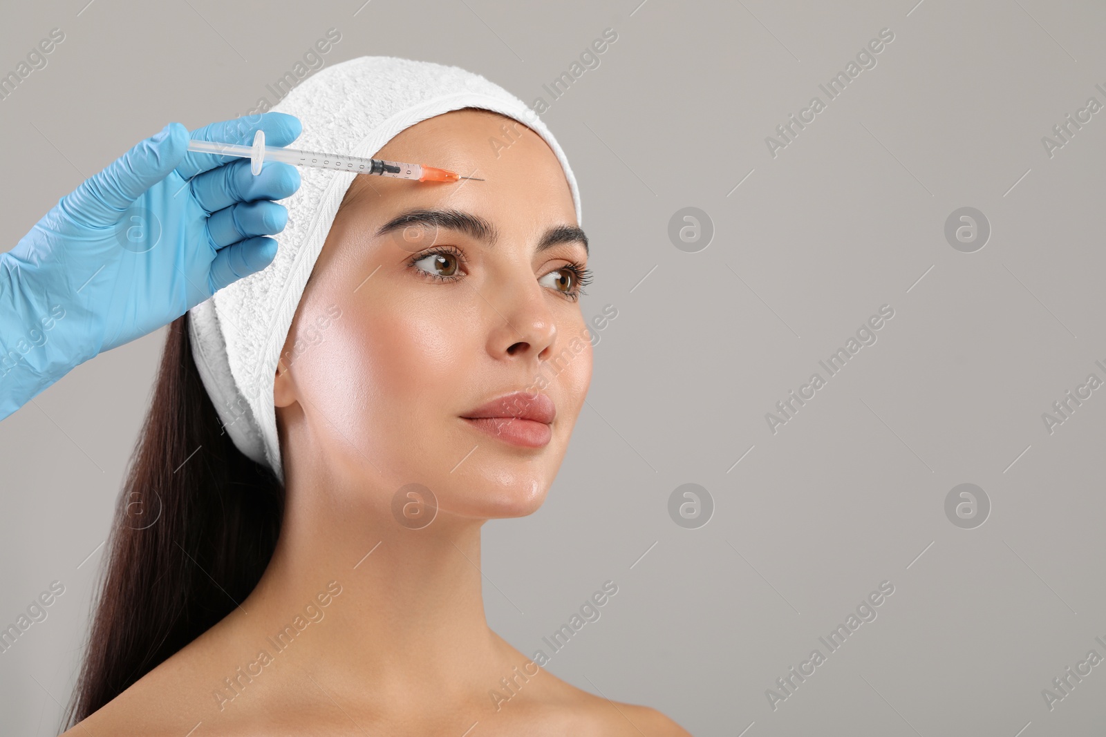 Photo of Doctor giving facial injection to young woman on light grey background, space for text. Cosmetic surgery