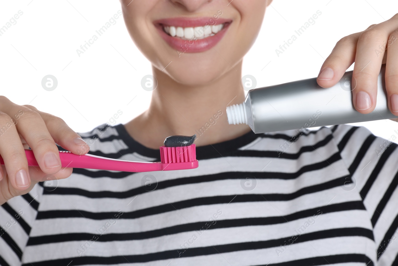 Photo of Woman applying charcoal toothpaste onto brush on white background, closeup