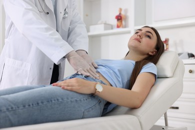 Gastroenterologist examining patient with stomach pain on couch in clinic, closeup