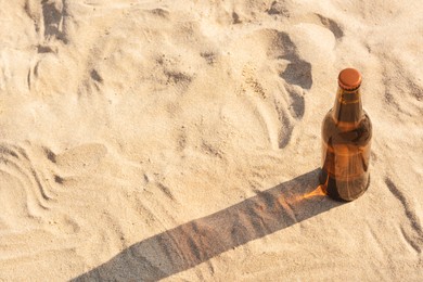 Bottle of beer on sandy beach, above view. Space for text