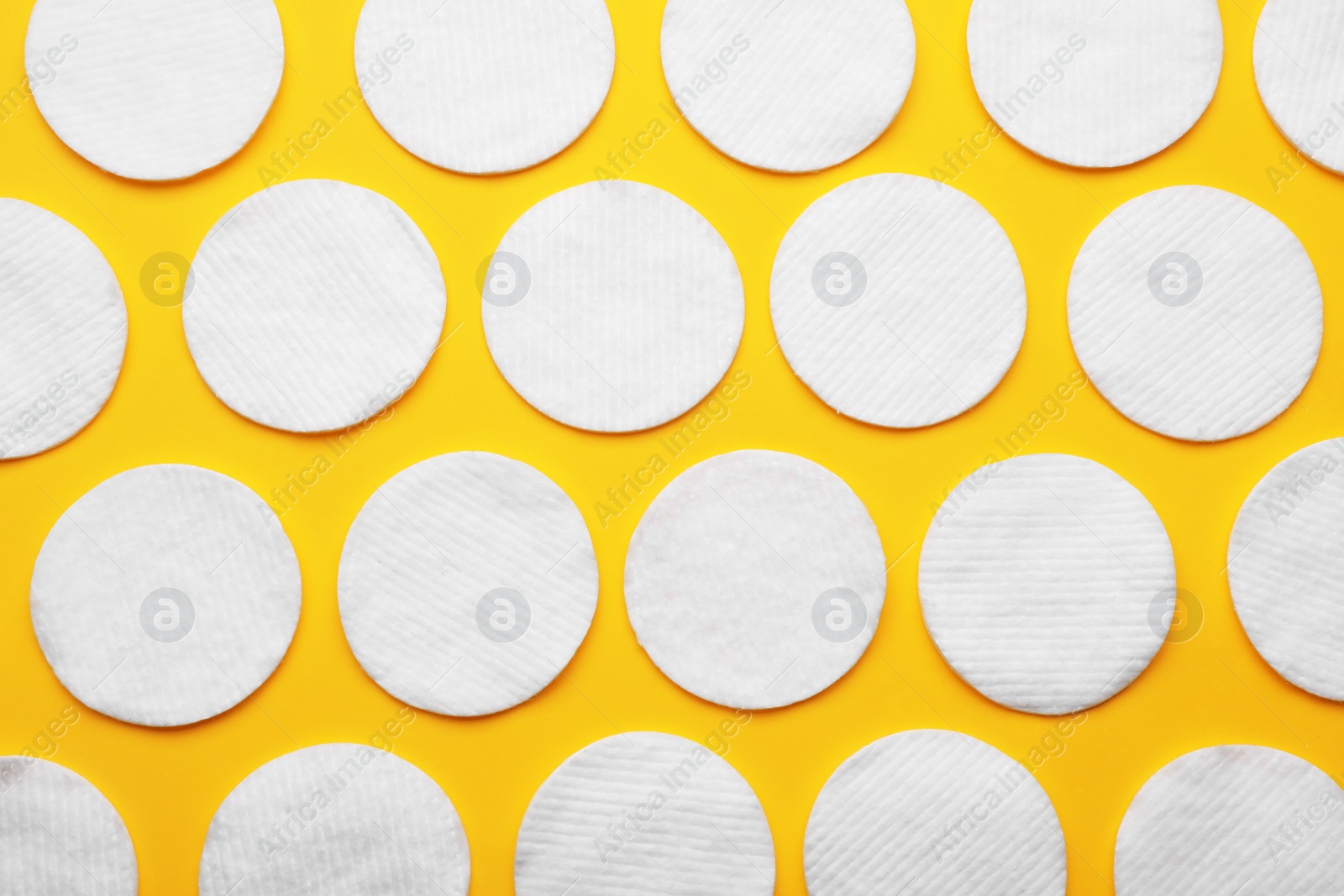 Photo of Soft clean cotton pads on yellow background, flat lay