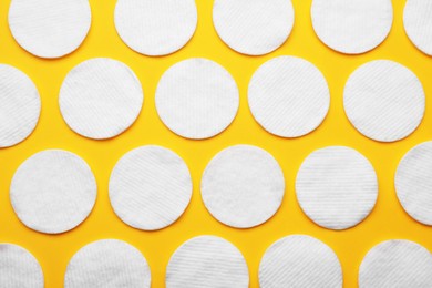 Photo of Soft clean cotton pads on yellow background, flat lay