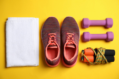 Photo of Flat lay composition with fitness equipment and shoes on yellow background