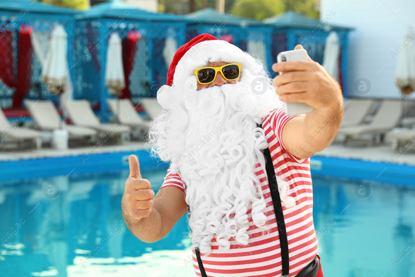 Photo of Authentic Santa Claus taking selfie near pool at resort