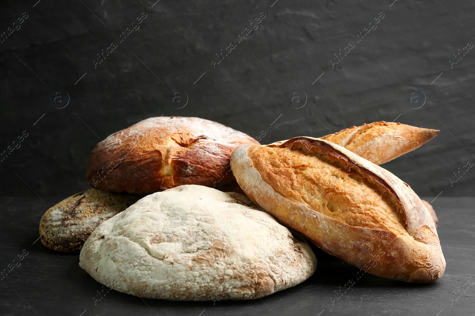 Photo of Different kinds of fresh bread on black table