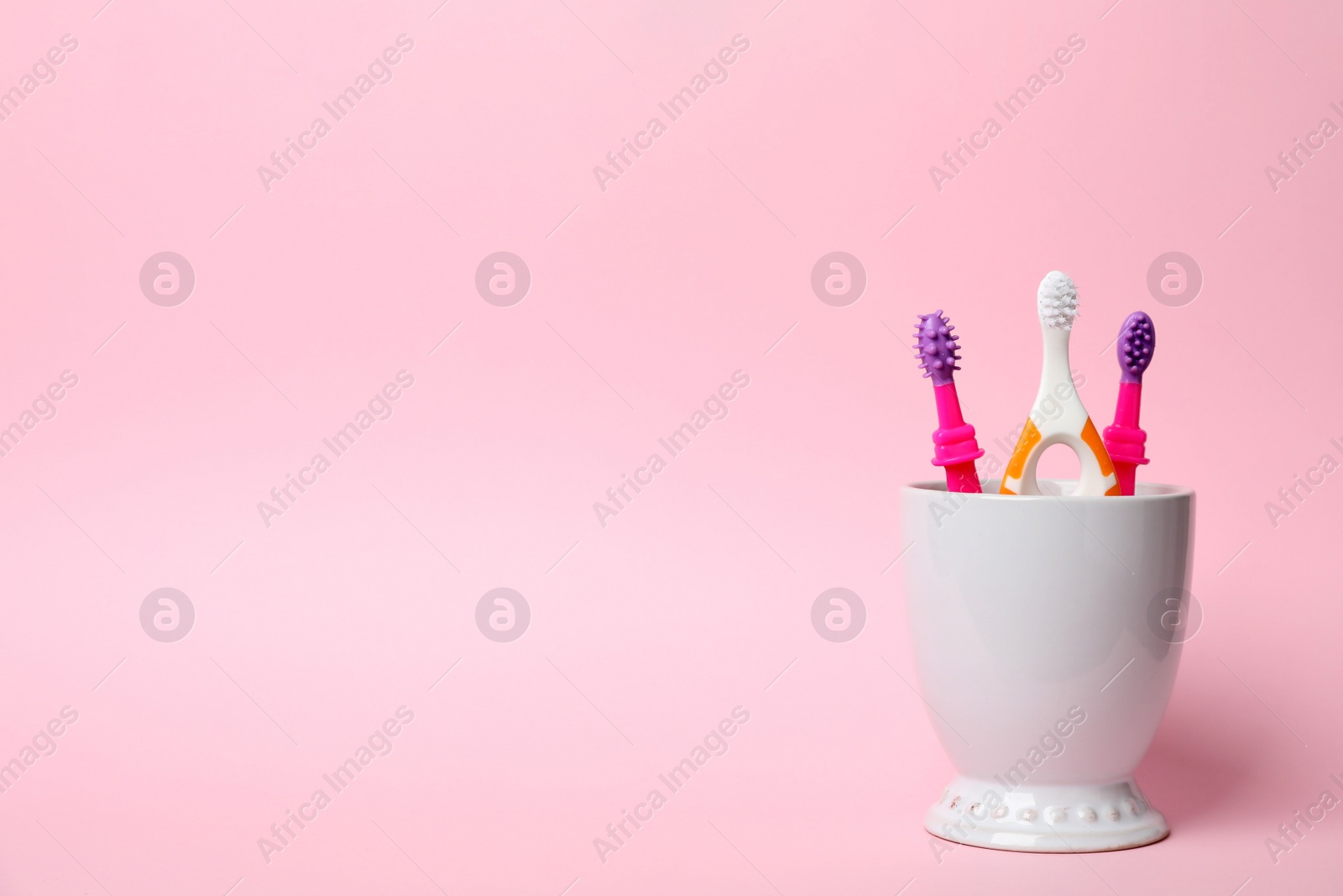 Photo of Baby toothbrushes in holder and space for text on color background