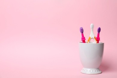 Baby toothbrushes in holder and space for text on color background