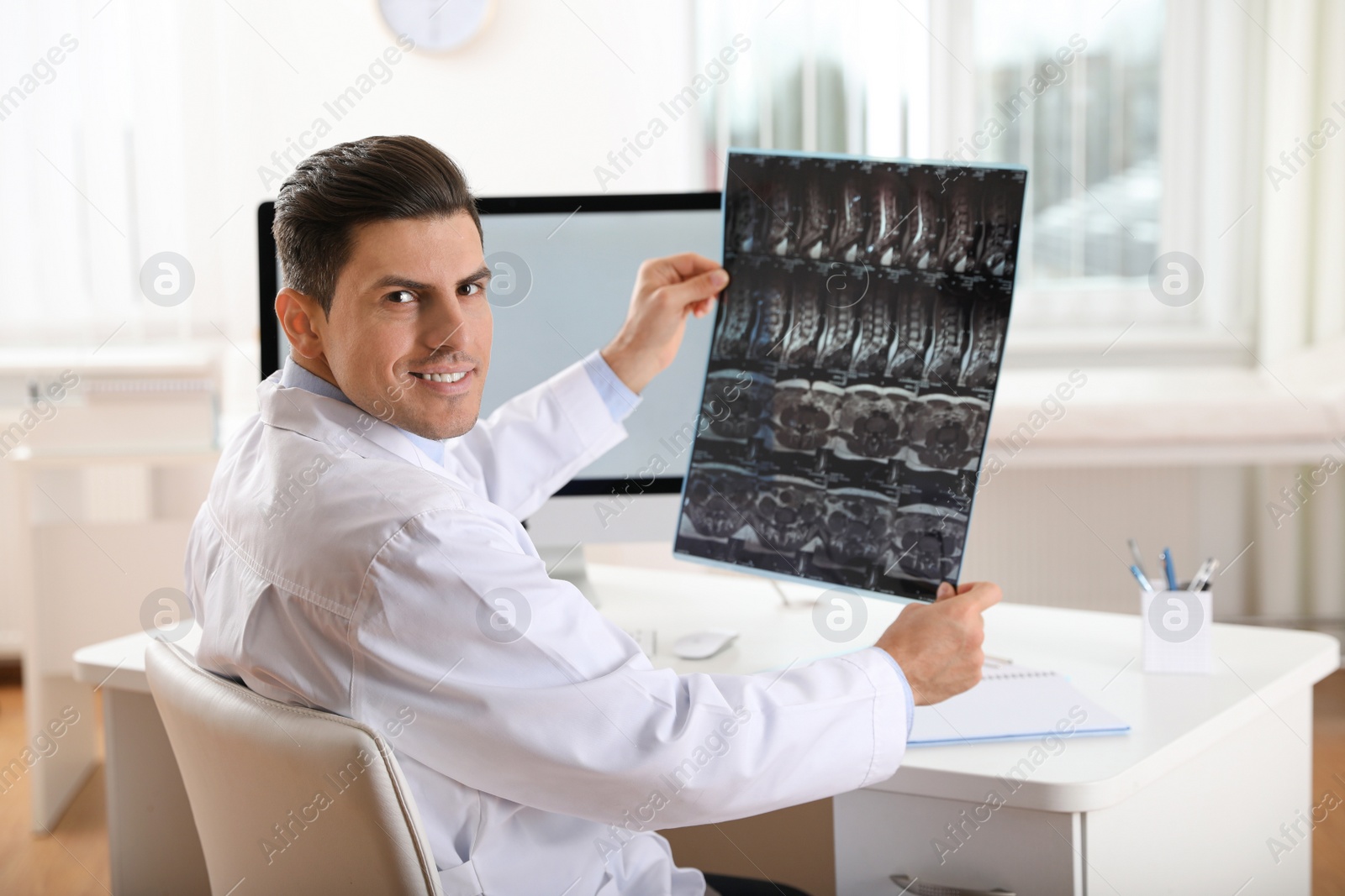 Photo of Orthopedist examining X-ray picture at desk in clinic