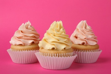 Tasty cupcakes with cream on pink background