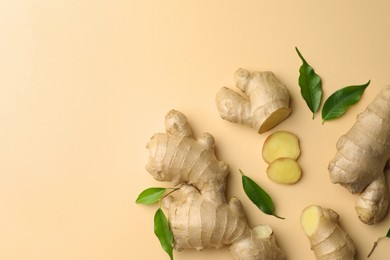 Photo of Fresh ginger with green leaves on beige background, flat lay. Space for text