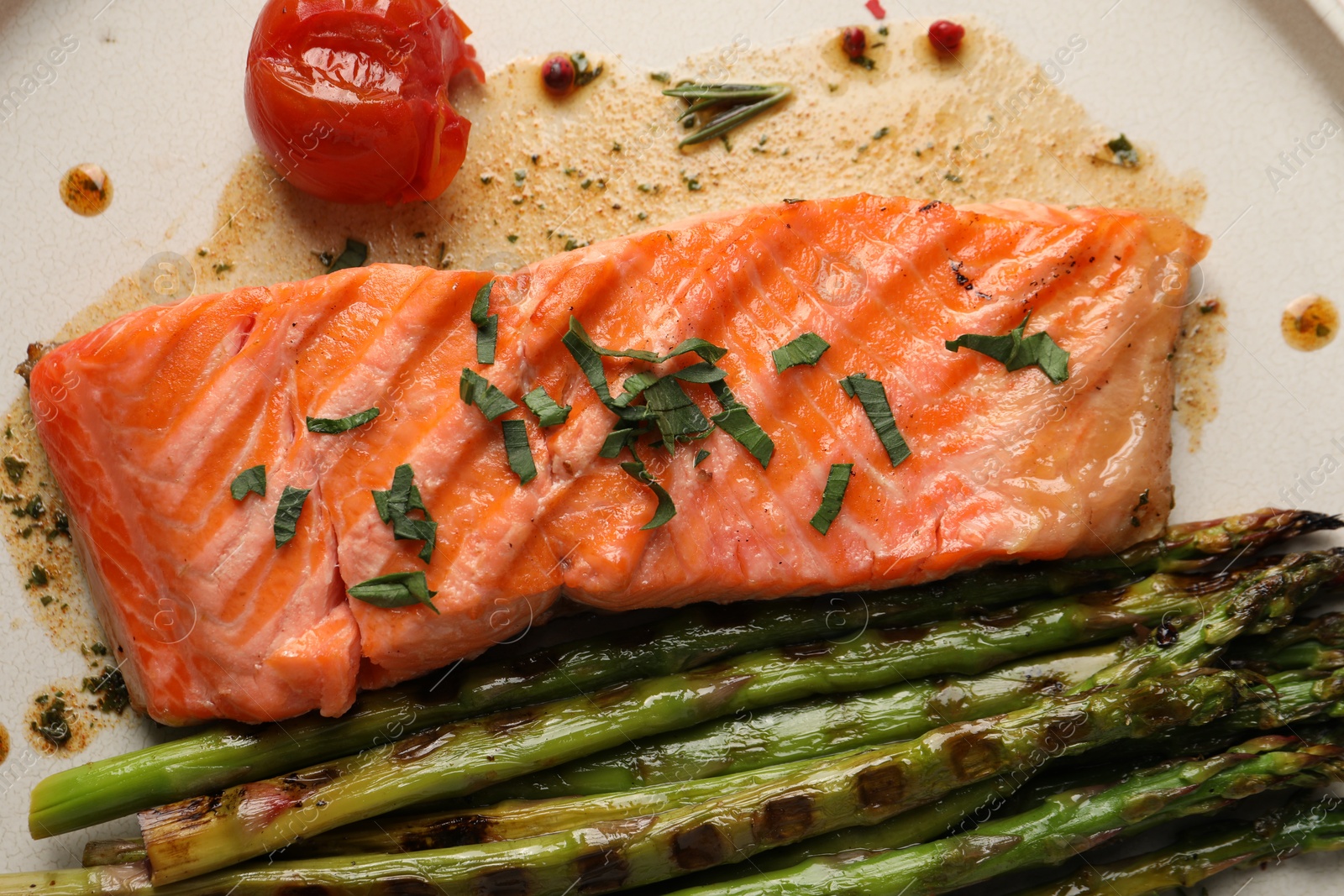 Photo of Tasty grilled salmon with tomato, asparagus and spices on plate, top view