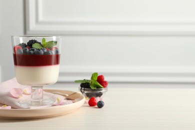 Photo of Delicious panna cotta with berries on white wooden table. Space for text