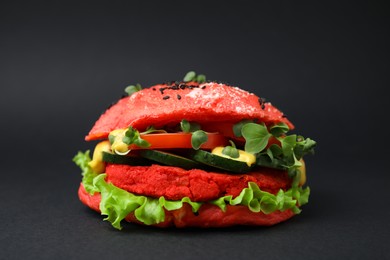 Tasty pink vegan burger with vegetables, patty and microgreens on black background, closeup