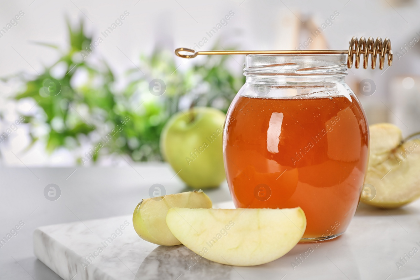 Photo of Jar of honey, apples and dipper on light table