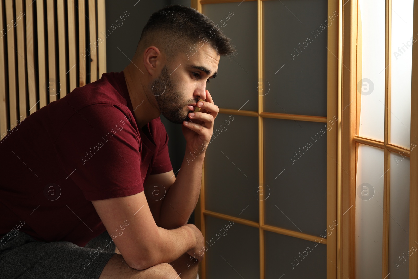 Photo of Sad young man at home. Space for text