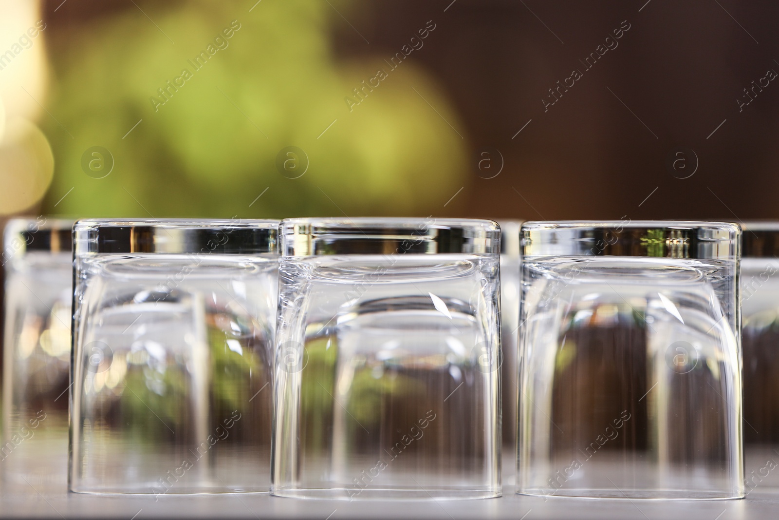 Photo of Set of empty glasses on grey table against blurred background