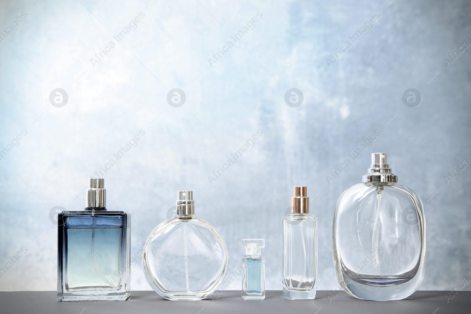 Photo of Different perfume bottles on table against color background