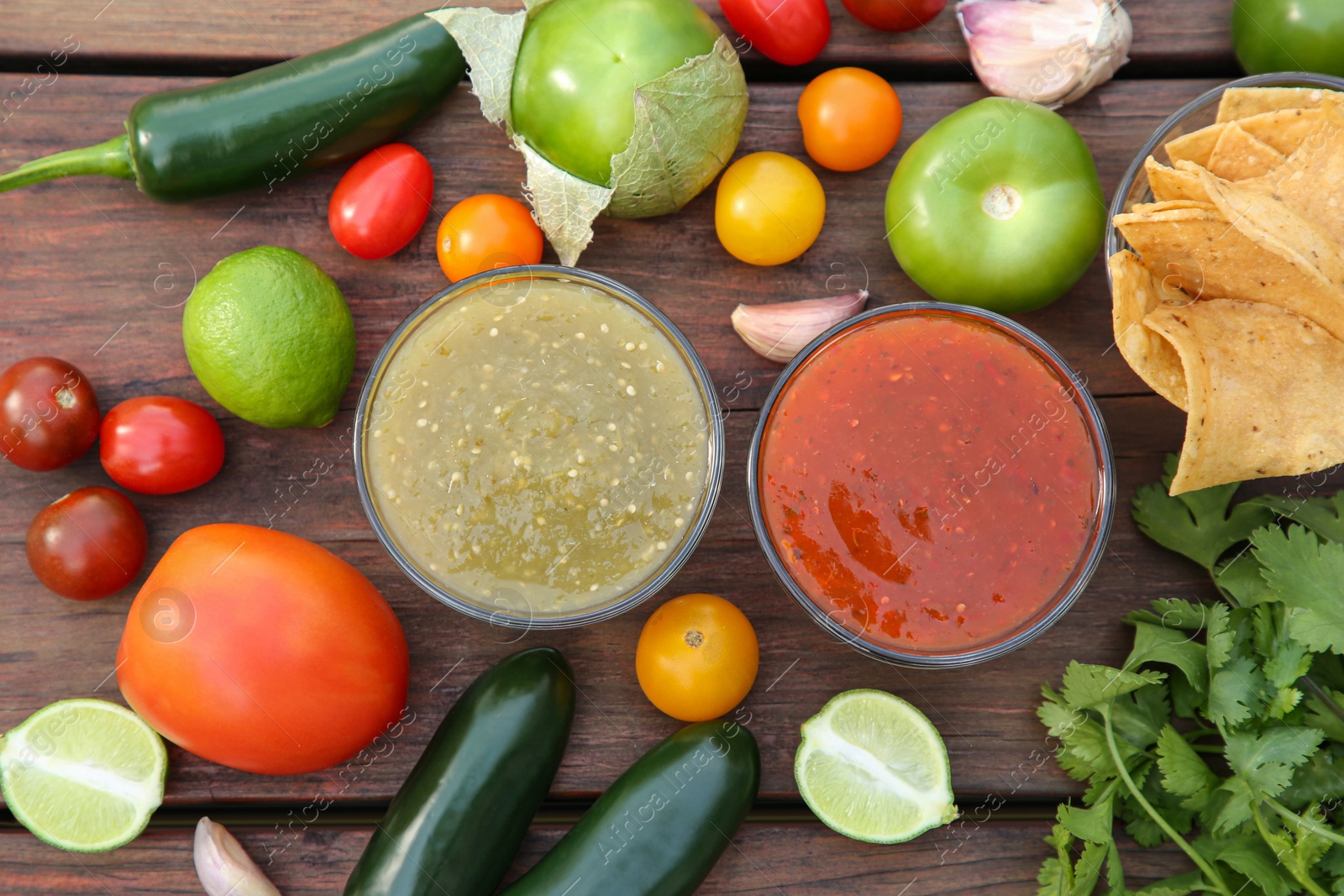 Photo of Flat lay composition of tasty salsa sauces and different ingredients on wooden table