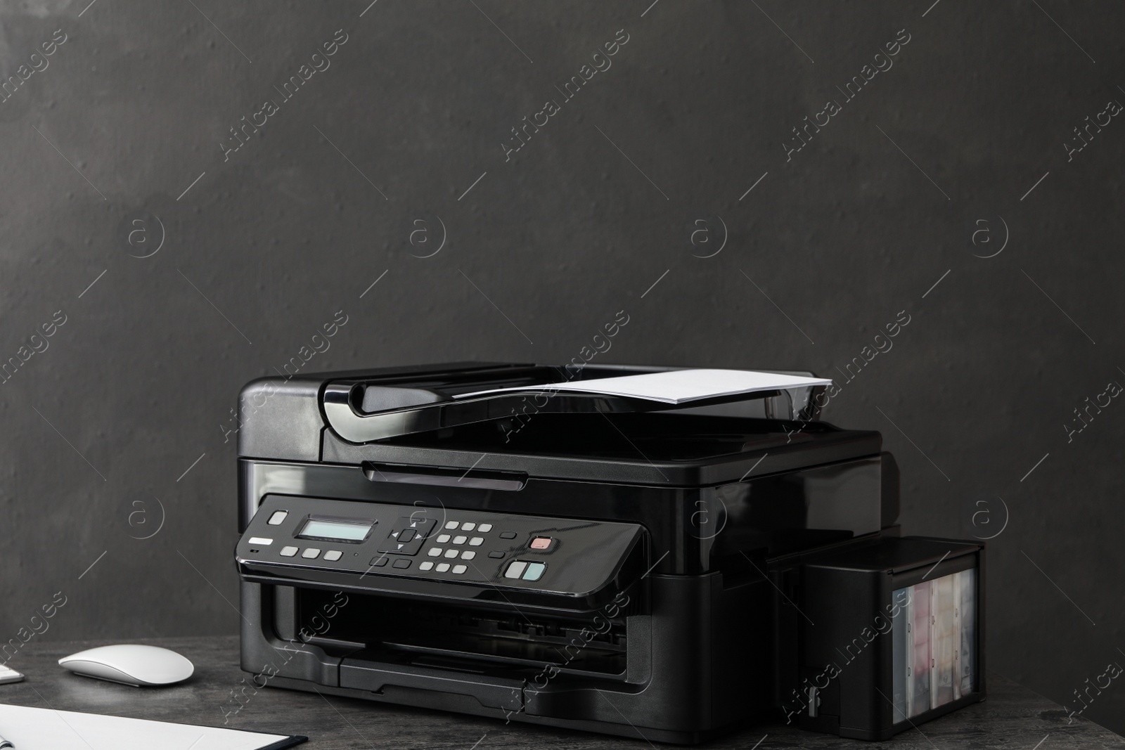 Photo of Modern printer with paper on grey table at workplace