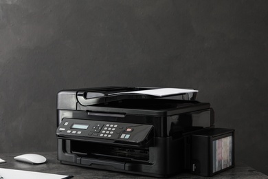 Photo of Modern printer with paper on grey table at workplace