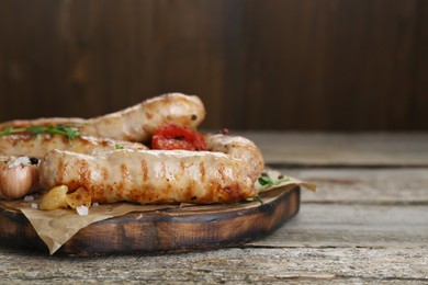 Photo of Tasty fresh grilled sausages with vegetables on wooden table, closeup. Space for text