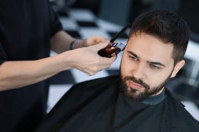 Photo of Professional hairdresser working with client in barbershop