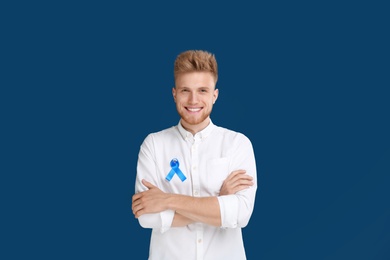 Young man with ribbon on blue background. Urology cancer awareness