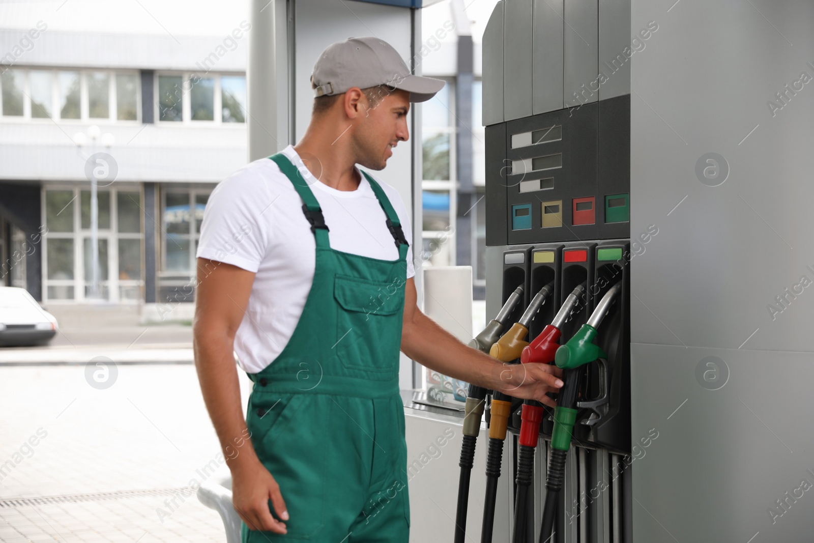 Photo of Worker taking fuel pump nozzle at modern gas station