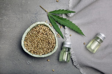 Flat lay composition with hemp seeds and bottles of extract on grey background