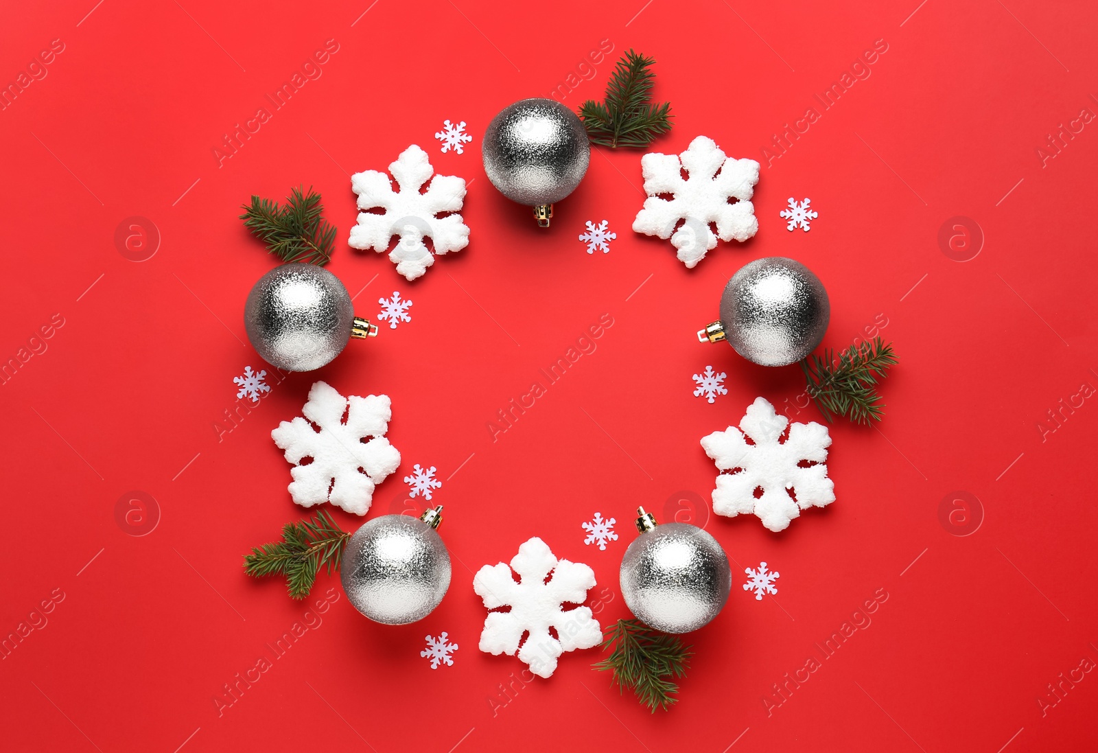 Photo of Beautiful festive wreath made of silver Christmas balls and snowflakes on red background, top view