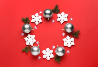 Photo of Beautiful festive wreath made of silver Christmas balls and snowflakes on red background, top view