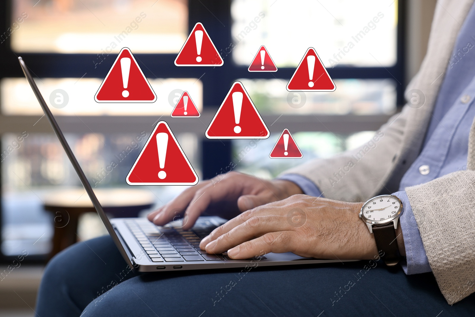 Image of Man using laptop at table, closeup. Warning signs for spam messages above device