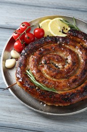 Delicious homemade sausage with spices, tomatoes and lemon on light grey wooden table