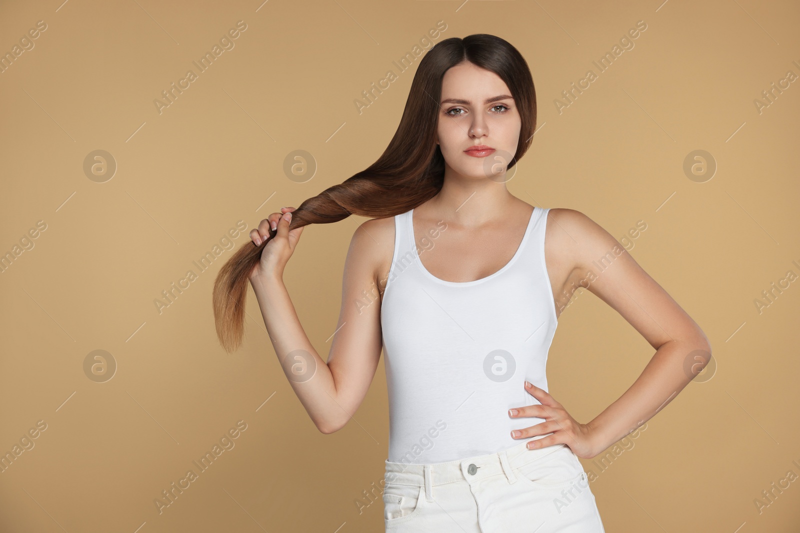 Photo of Young woman with strong healthy hair on beige background