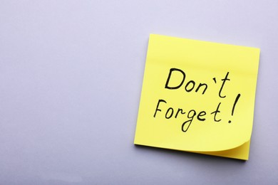 Photo of Paper note with phrase Don't Forget on light grey background, top view. Space for text