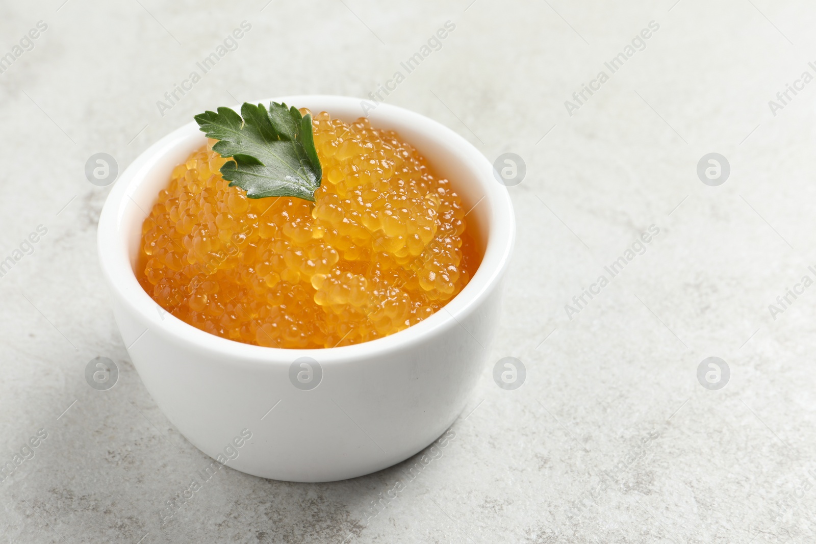 Photo of Fresh pike caviar and parsley in bowl on light grey table