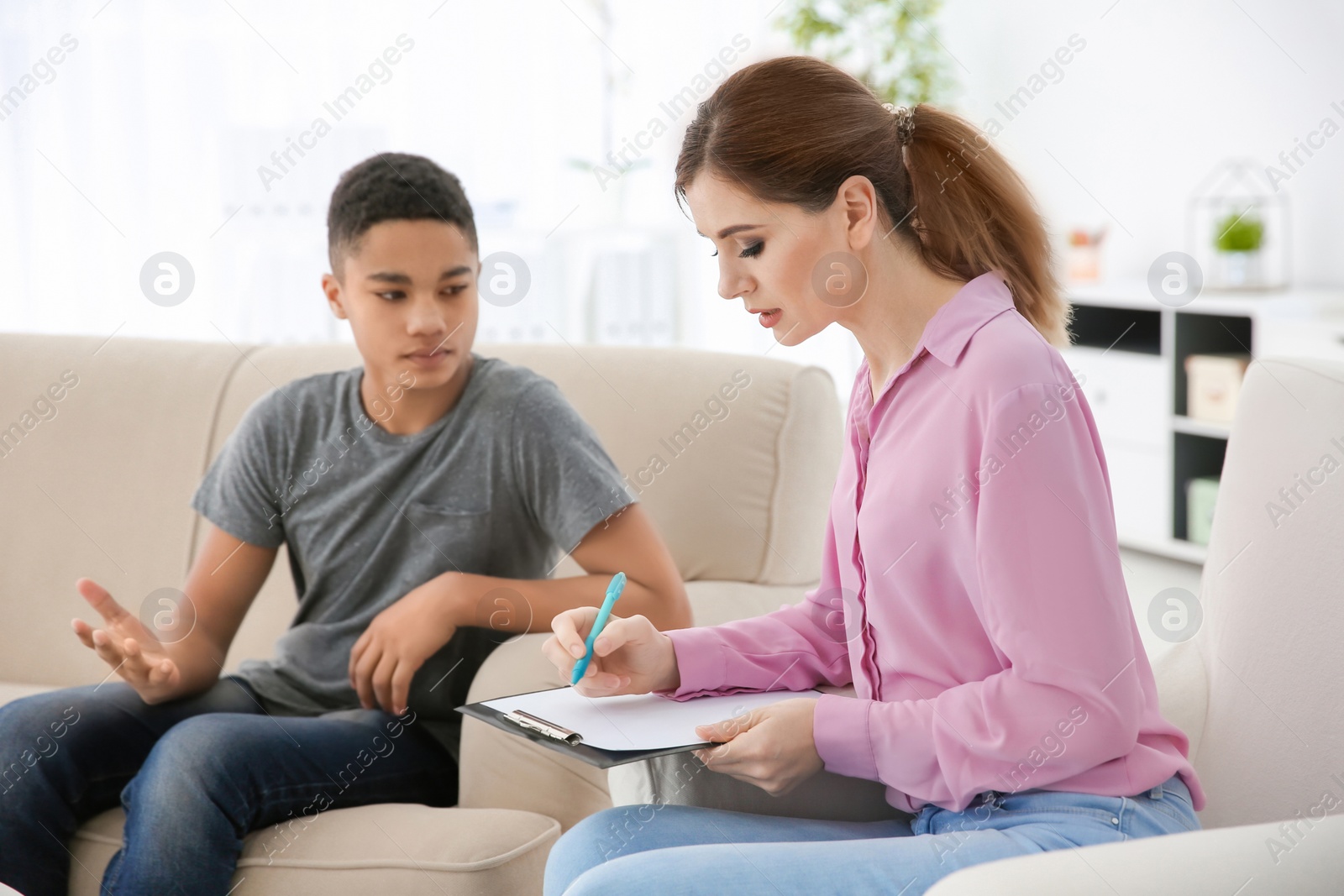 Photo of Female psychologist working with African American teenage boy in office