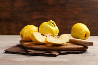 Photo of Ripe whole and cut quinces with knife on wooden table