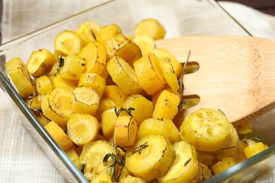 Photo of Baked yellow carrot and wooden fork in glass dish on table, closeup