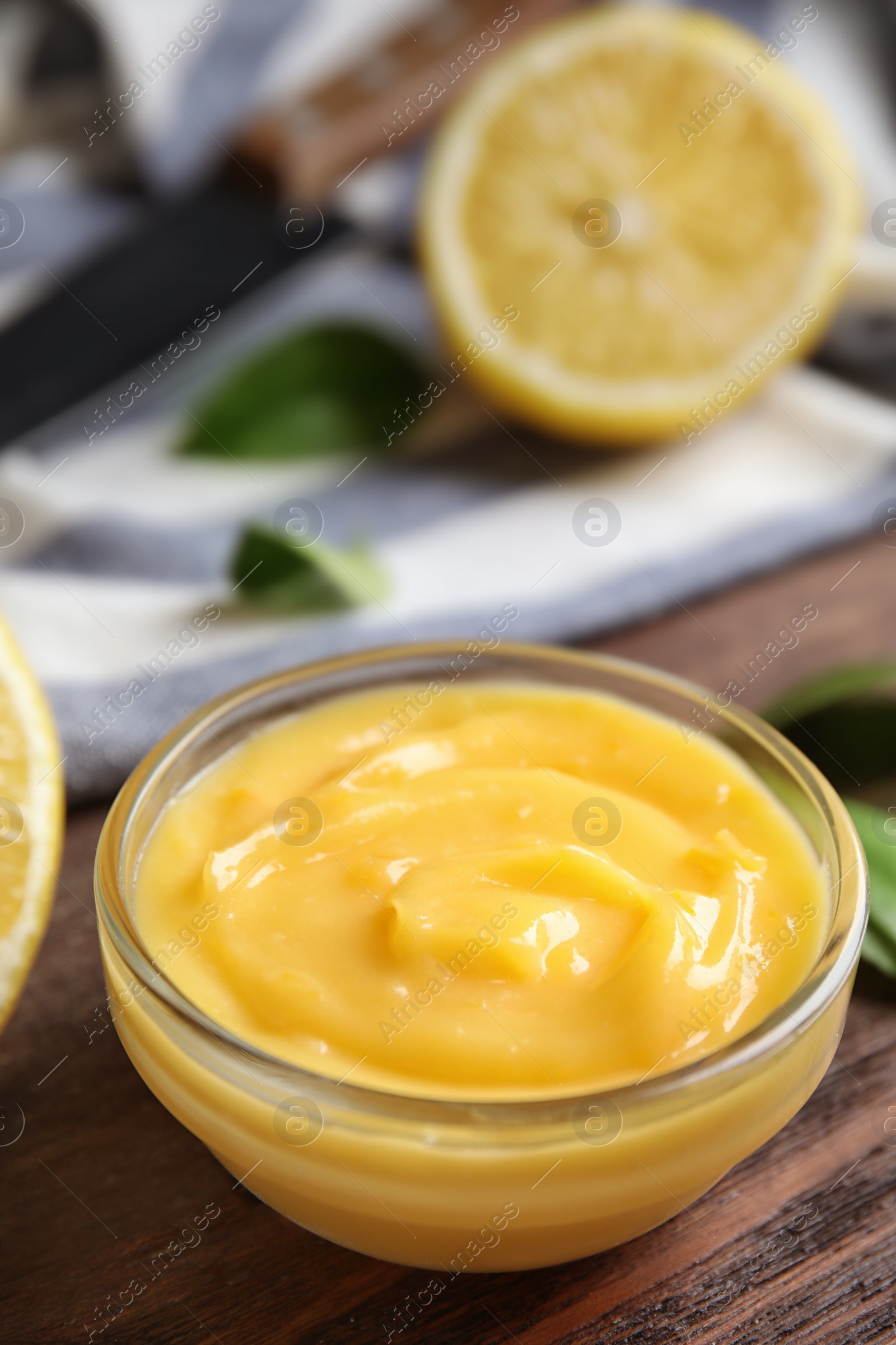 Photo of Delicious lemon curd in bowl on wooden table. Space for text