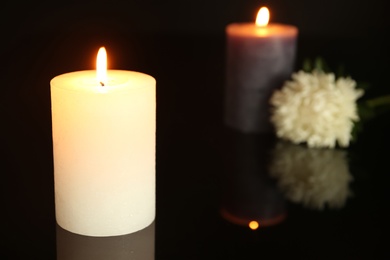 Photo of Burning decorative candles with flower on black background