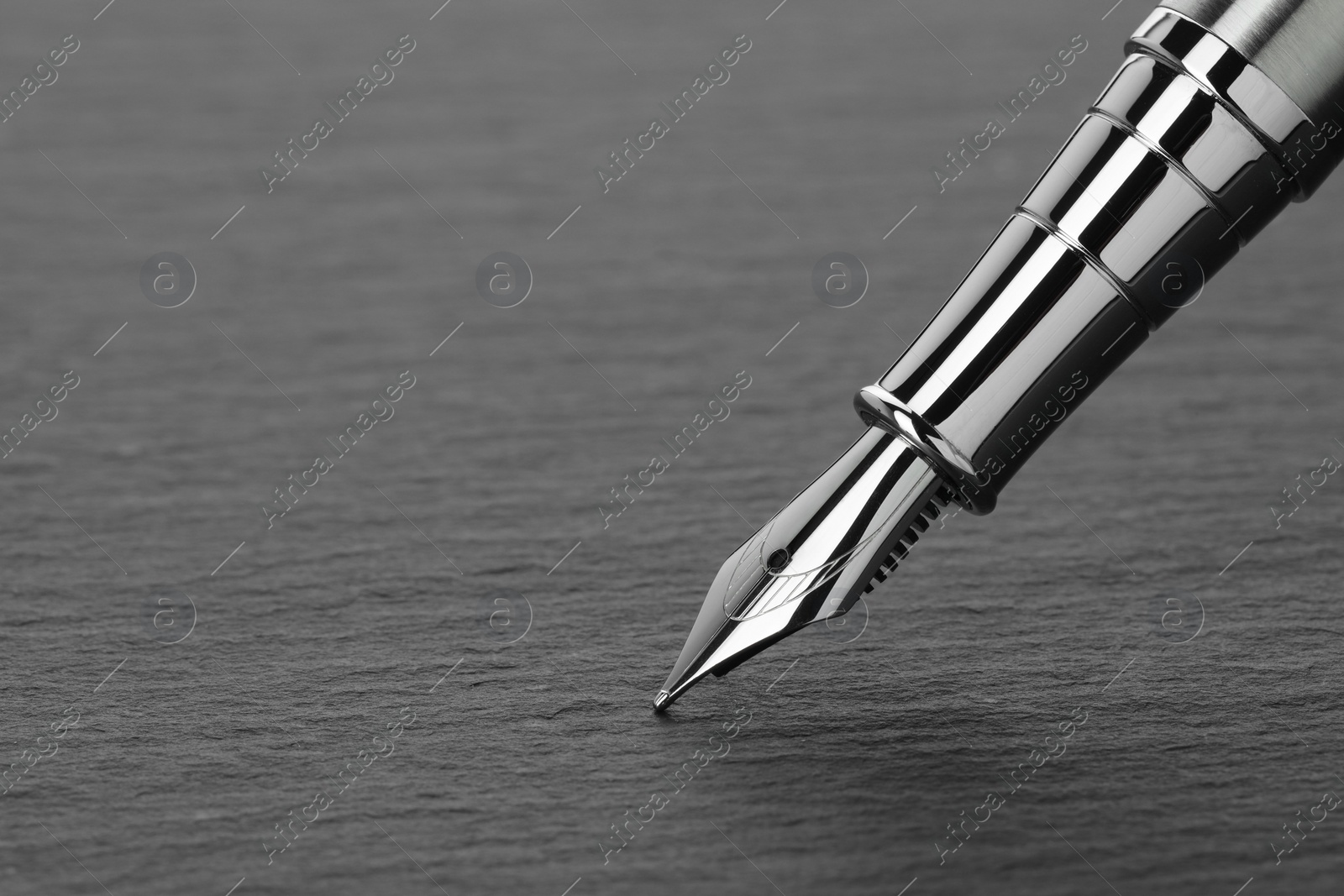 Photo of Stylish fountain pen on dark textured table, closeup. Space for text