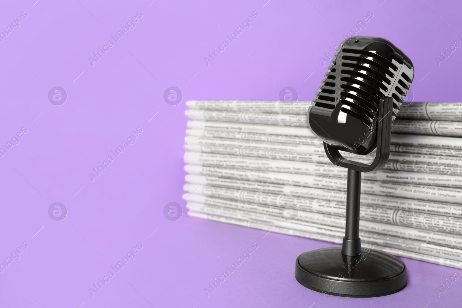 Photo of Newspapers and vintage microphone on light violet background, space for text. Journalist's work