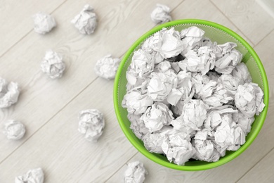 Photo of Metal bin and crumpled paper on floor, top view. Space for text