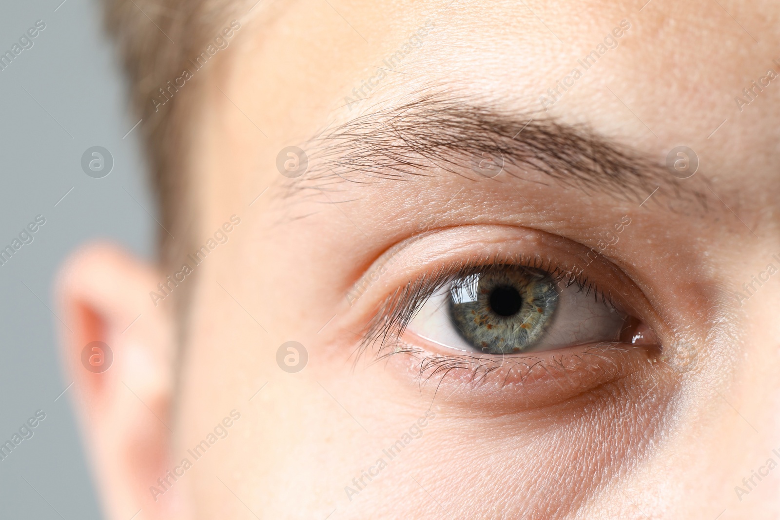 Photo of Perfect vision. Man with beautiful eyes on grey background, closeup