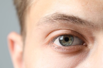 Perfect vision. Man with beautiful eyes on grey background, closeup