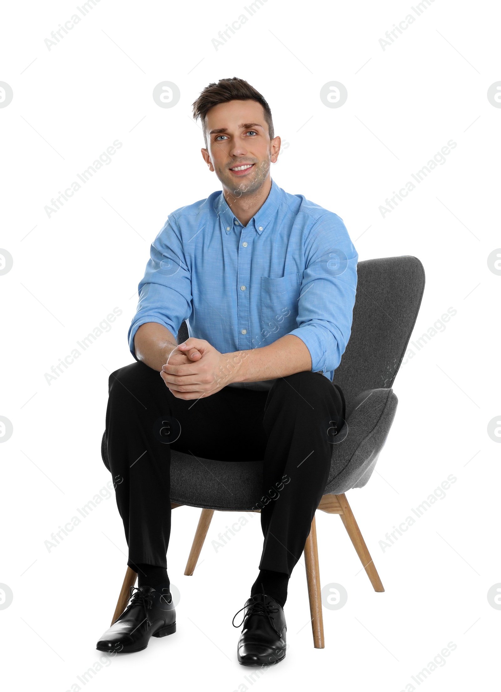 Photo of Handsome young man sitting in armchair on white background